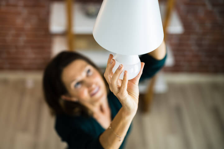 Kvinne bytter ut en vanlig lyspære med LED-pære